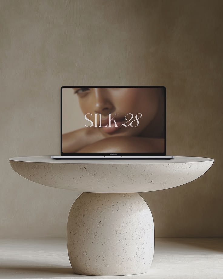 Mockup de un diseño de sitio web de la marca Silk 28 en una laptop sobre una mesa de piedra