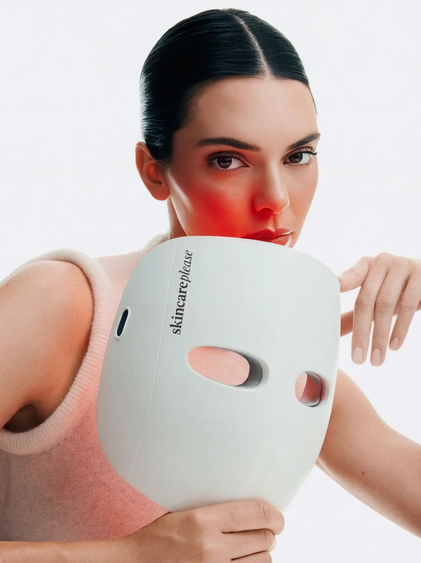 Modelo sosteniendo la máscara LED blanca de Skincare Please con luz roja